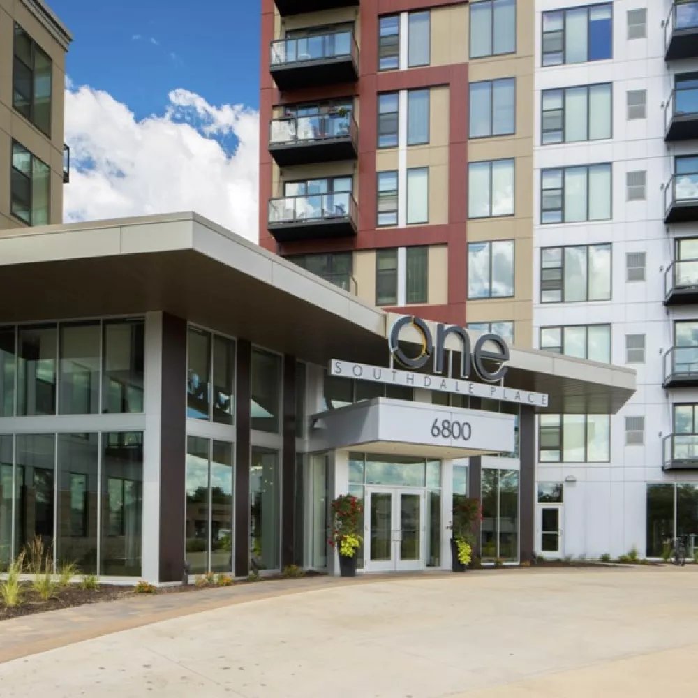 Modern high-rise building with a covered entrance marked "ONE 4800", featuring balconies and a colorful facade.