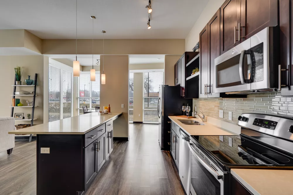 Modern kitchen with dark wood cabinets, light countertops, stainless steel appliances, and a central island.